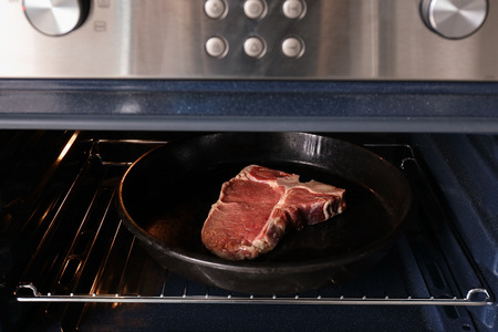 Pan with raw steak in oven