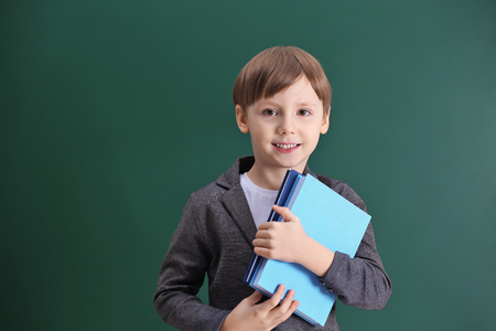 Cute little boy on school blackboard backgroundの写真素材