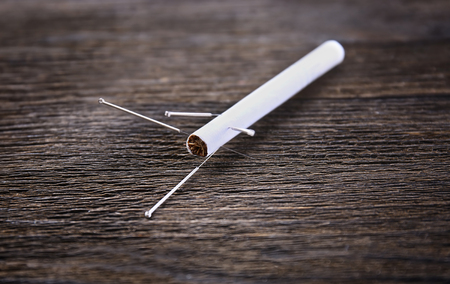 Acupuncture needles with cigarette on wooden backgroundの写真素材