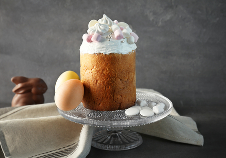 Vintage cake stand with traditional Russian Easter bread and painted eggs on gray background