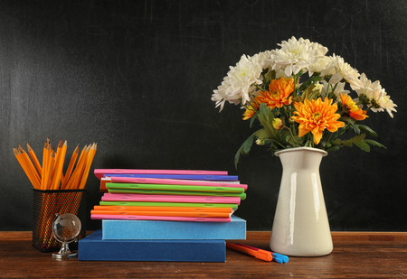 Bouquet of flowers, copybooks and books on wooden tableの写真素材