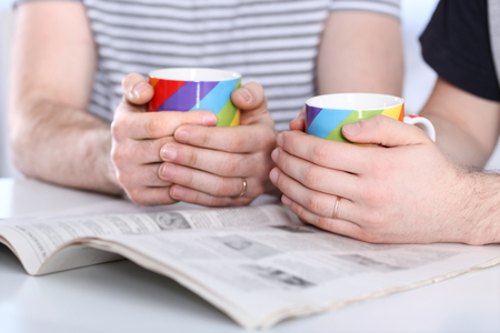 Happy gay couple holding coffee cupsの写真素材