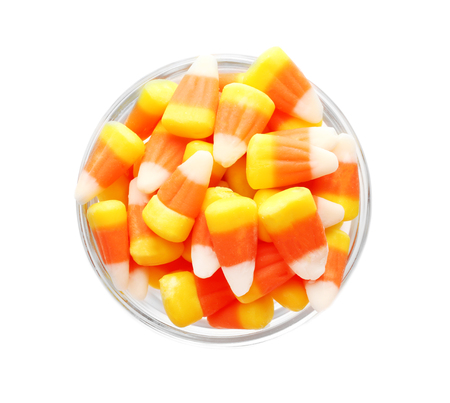 Colorful Halloween candy corns in bowl on white background