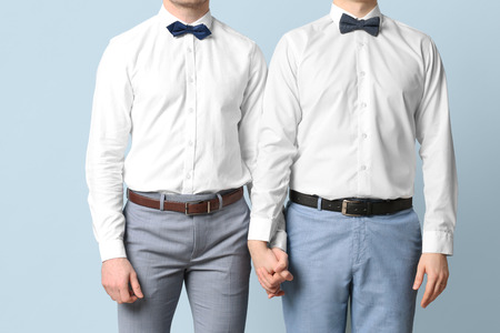 Happy gay couple holding hands together on color backgroundの写真素材