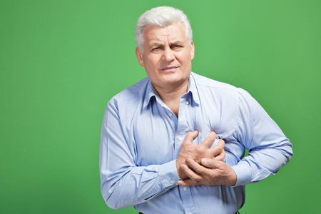 Man with chest pain suffering from heart attack on color background
