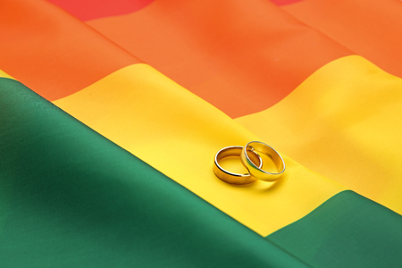 Two wedding rings on rainbow gay flag backgroundの写真素材