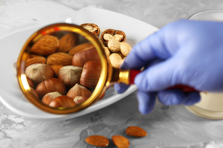 Scientist inspecting nuts under magnifying glassの写真素材