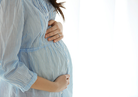 Beautiful pregnant woman on light background, closeup