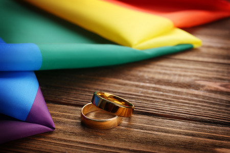 Two wedding rings and rainbow gay flag on wooden backgroundの写真素材