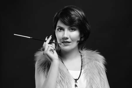 Young woman with cigarette holder on dark background