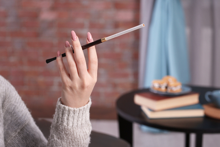 Female hand with cigarette holder on blurred backgroundの写真素材