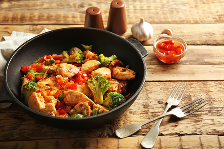 Chicken stir fry with cutlery and spices on tableの写真素材