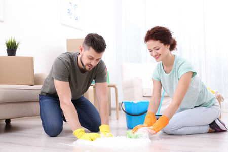 Happy young couple cleaning home togetherの写真素材