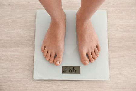 Diet concept. Female bare feet standing on scales
