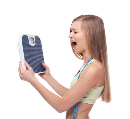 Diet concept. Young beautiful woman holding scales on white backgroundの写真素材