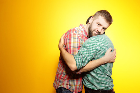 Happy gay couple posing on yellow backgroundの写真素材