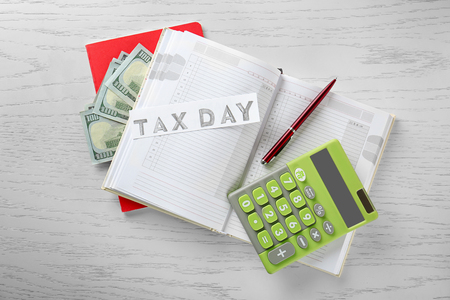 Calculator with money and notebook on wooden background. Tax conceptの写真素材
