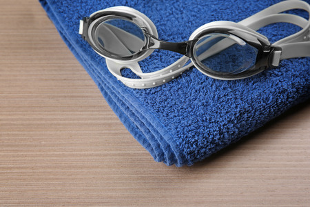 Swimming goggles with towel on wooden backgroundの写真素材