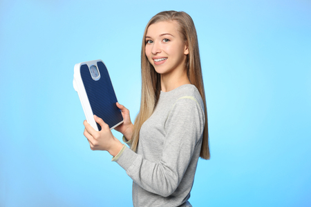 Diet concept. Young beautiful woman holding floor scales on light backgroundの写真素材