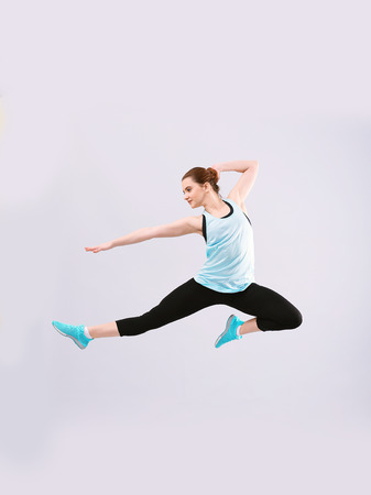 Young beautiful fitness girl training on light backgroundの写真素材