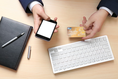 Hands of man with credit card and mobile phone in office