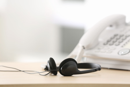 Black headset on table of technical support agent in officeの写真素材