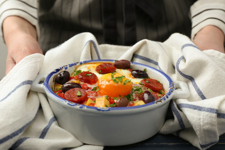 Woman holding baking dish with delicious Spanish baked eggの写真素材