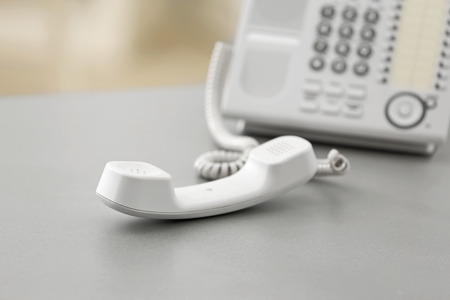 Telephone with picked up receiver on table in officeの写真素材