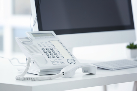 Telephone with picked up receiver on table in officeの写真素材