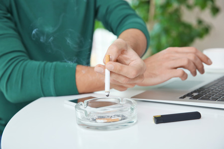 Male hand ashing his cigarette into ashtray, closeupの写真素材