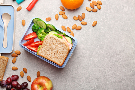 Lunch box with delicious food, fruits and almond on light textured backgroundの写真素材
