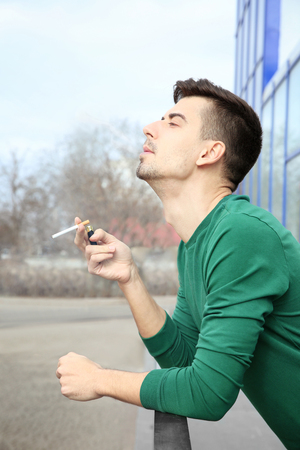 Young man smoking cigarette outdoorsの写真素材