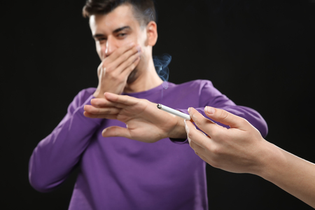 Passive smoking concept. Young man covering face from cigarette smokeの写真素材