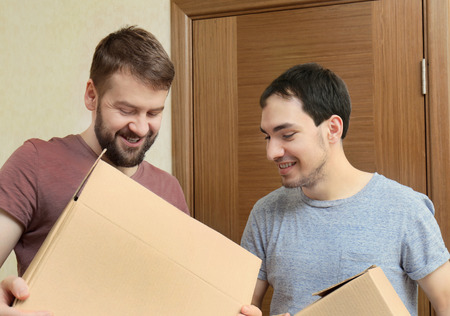 Gay couple unpacking cardboard boxes at homeの写真素材