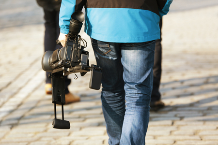 Walking man holding professional camcorder outdoorsの写真素材