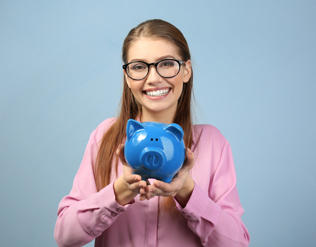 Beautiful young woman with piggy bank on color backgroundの写真素材