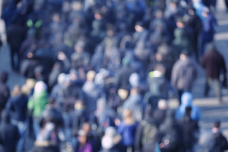 Crowd of people walking on busy city street, blurred view