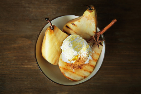Bowl with pears and ice cream on wooden tableの写真素材