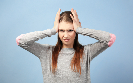 Beautiful young woman suffering from headache on color backgroundの写真素材