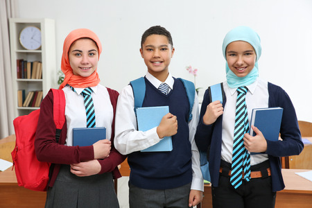 Schoolchildren standing in classroom with booksの写真素材