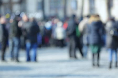 Crowd of people walking on busy city street, blurred view