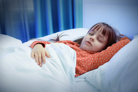 Little cute girl sleeping in bedの写真素材