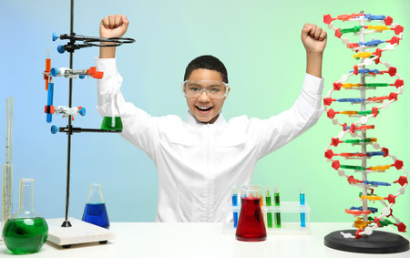 Happy school boy sitting at workplace in chemistry classの写真素材
