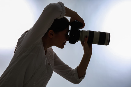 Female photographer with professional camera on white backgroundの写真素材
