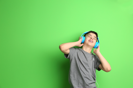 Teenager with headphones listening to music on color backgroundの写真素材
