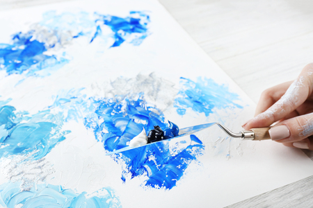 Female hand painting abstract picture with oil paint strokes, closeupの写真素材