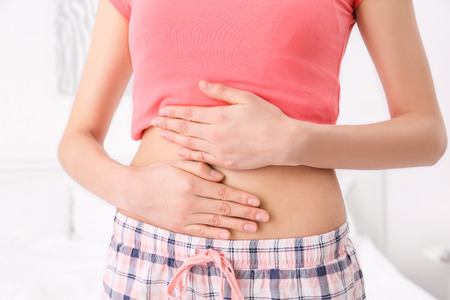 Young woman with hands on her belly at home, closeupの写真素材