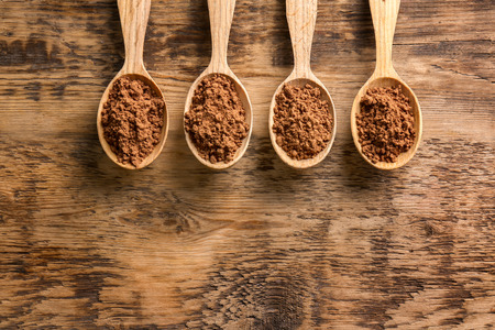 Spoons with cocoa powder on wooden backgroundの写真素材