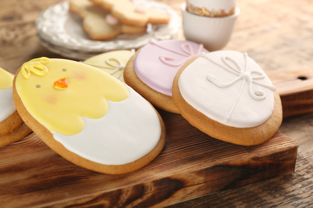 Wooden board with creative egg shape Easter cookies on table