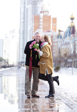 Happy senior couple with bouquet of flowers  on a walkの写真素材